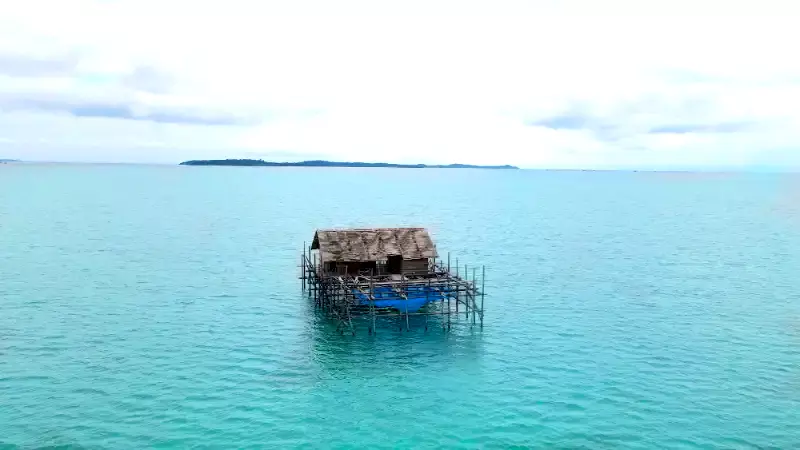 Small, rustic pontoon hut floating in the middle of clear turquoise water, serving as a dedicated fishing spot for the Ponton Fishing activity at batam beach resort.