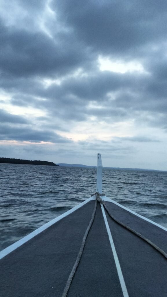 Dramatic sunset scene over the beach, featuring colorful clouds and the silhouette of a tent-structure and seating area at Kiki Beach.