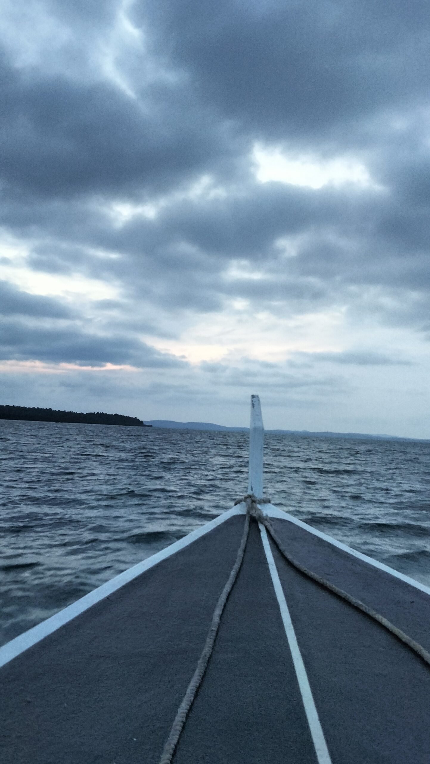 Dramatic sunset scene over the beach, featuring colorful clouds and the silhouette of a tent-structure and seating area at Kiki Beach.