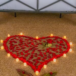 Heart shape made of red rose petals and small candles on the floor, set up for a romantic anniversary or honeymoon surprise at Kiki Beach Island Resort.