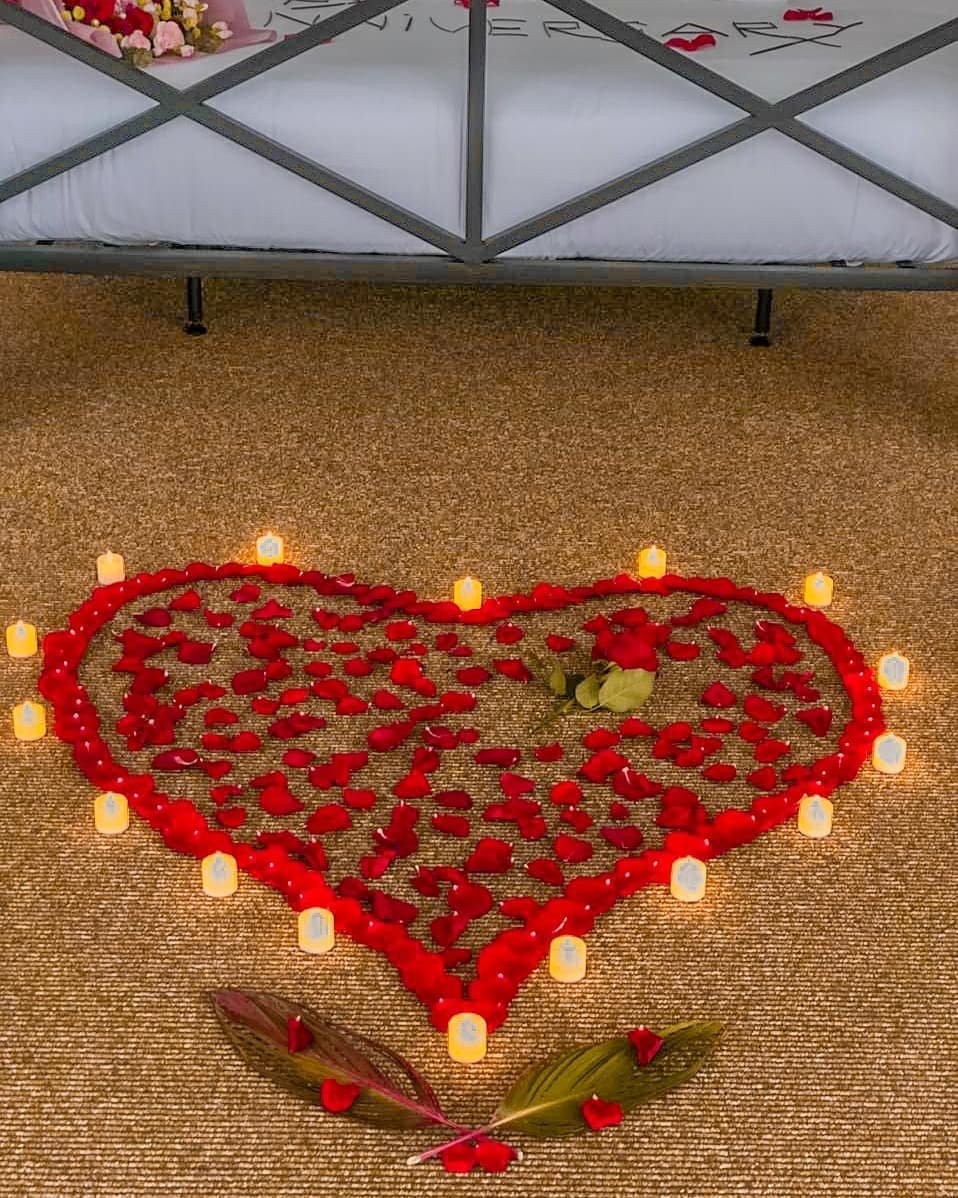 Heart shape made of red rose petals and small candles on the floor, set up for a romantic anniversary or honeymoon surprise at Kiki Beach Island Resort.